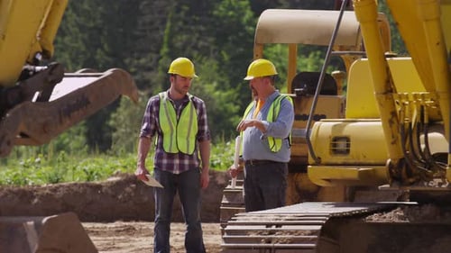 Two workers talking by machinery