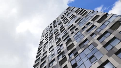 Industrial Climbers Cleaning the Exterior Windows of a Skyscraper with Blue Sky and Clouds on