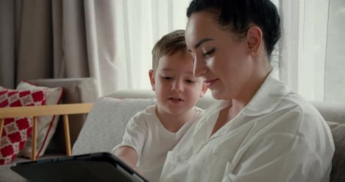 Woman and Child Using Tablet Together on Couch