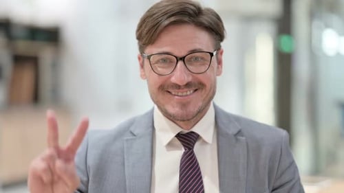Smiling Man Giving Peace Sign in Office Setting