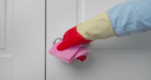 Hand With Gloves Wiping Doorknob With Cloth