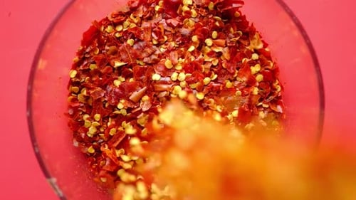 Adding crushed red pepper flakes to full bowl