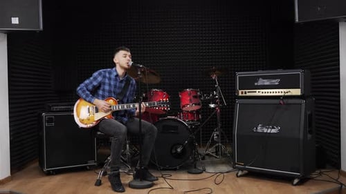 Man Sings and Plays Guitar in Recording Studio