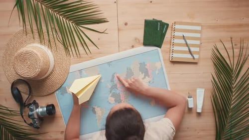 Person Planning Vacation with Map and Paper Airplane