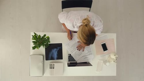 Young and Professional Doctor Works with Lots of Documents in Office