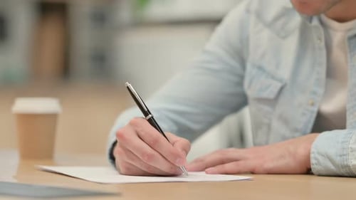 Nahaufnahme eines kreativen jungen Mannes, der auf Papier schreibt