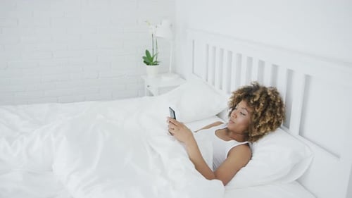 Woman Lies in Bed Using a Smartphone
