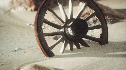 Old Broken Wooden Wagon Wheel Buried in Desert Sand