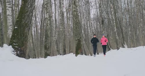 Man and Woman Run in the Park in Winter in Slow Motion