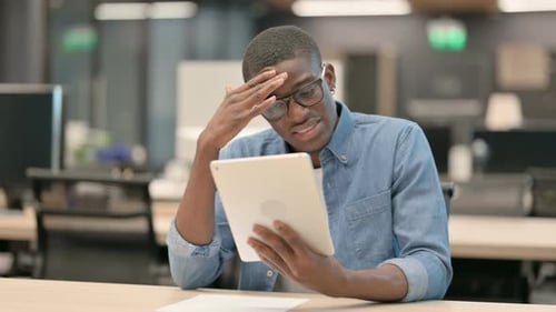 Young African American Man Having Loss on Tablet in Office
