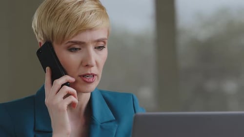 Woman Talking on Phone While Working at Laptop