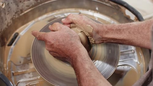 Un potier professionnel transforme de l'argile humide sur la roue de potier et lui donne forme à un futur produit en gros plan