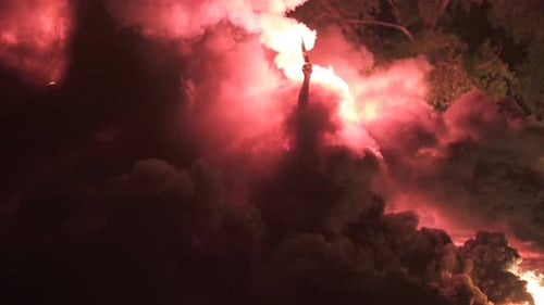 Flare Ignites in Dense Red Smoke at Night