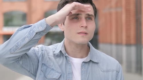 Man Shields Eyes, Searching in Urban Environment