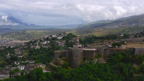 Panoramic aerial view of Gjirokaster Castle and city old town on background, under cloudy sky