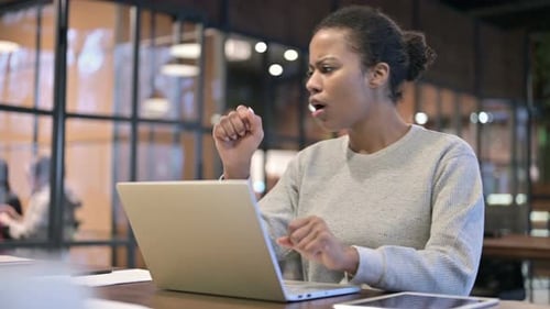 Young Woman Coughing While Working on Laptop