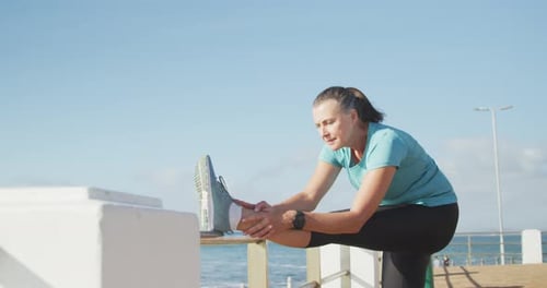 Senior woman stretching her legs on a promenade