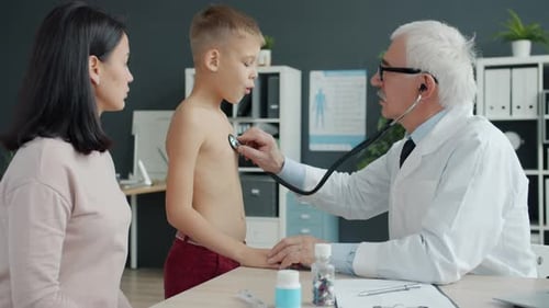 Pediatrician Examining Child in Hospital Using Stethoscope While Mother Watching Boy