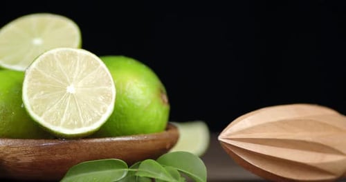 Fresh Limes in Wooden Bowl with Citrus Reamer