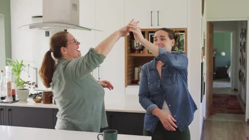 Smiling Women Dancing Together in Bright Kitchen