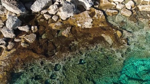 Aerial Top View Footage By Drone of Ocean Blue Water and Rocks A Calm Sea Washes the Rocky Mountain