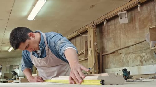 Craftsman Measures Wood in Woodshop
