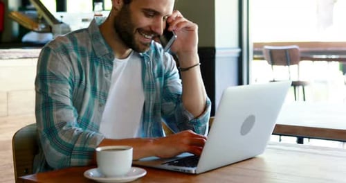 Man Working at Cafe on Laptop and Phone