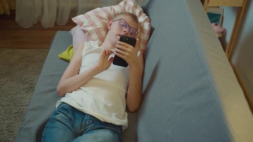 Young Adult Using Phone While Lying on Couch