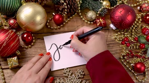 Hands Write January on Holiday-Themed Background