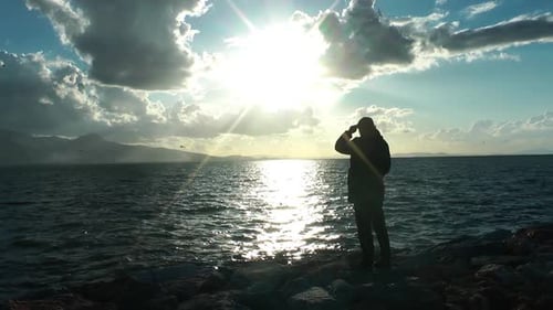 Seul homme célibataire debout face à la mer et au soleil