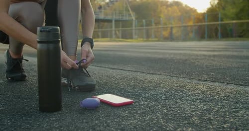 Woman Tying Shoelaces on Outdoor Track