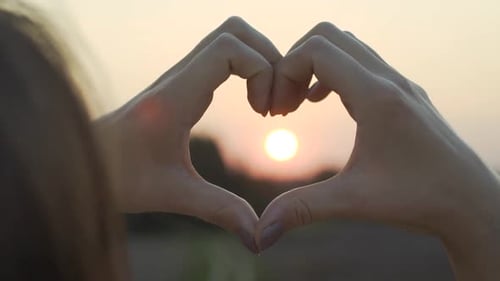 Hands Make Heart Shape at Colorful Sunset