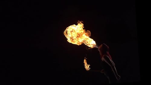 Woman Blows Fire in the Darkness