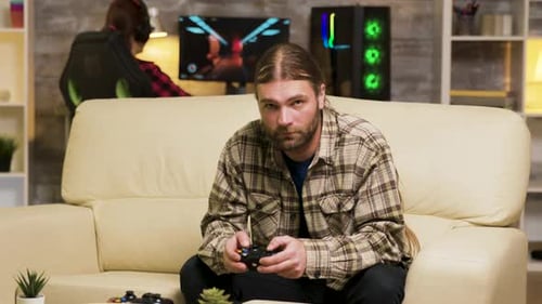 Man Plays Video Game on Sofa at Home