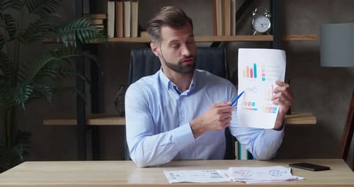Man Presenting Colorful Charts at Desk