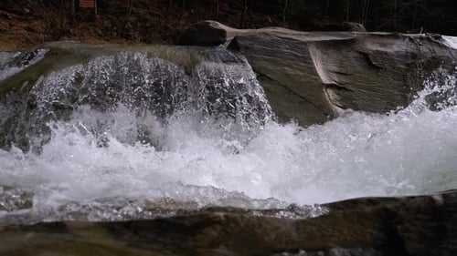 Mountain Creek and Stone Rapids with Snow. Rapid Flow of Water. Winter Waterfall. Slow Motion