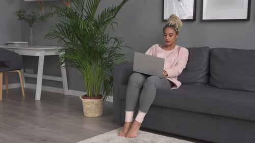 Woman Using Laptop on Couch in Modern Living Room