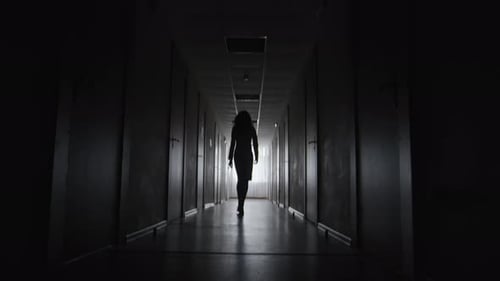 Silhouette Woman Walking Down a Dark Hallway