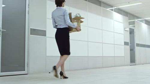 Female Employee Walking with Belongings though Hallway in Office Center