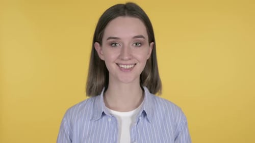 Woman Smiles Towards Camera Against Yellow Background