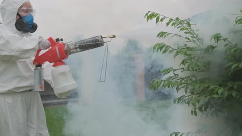 Landwirt, Agronom in Schutzanzug und Atemschutzmaske, behandelt Obstbäume vor Schädlingen und Krankheiten