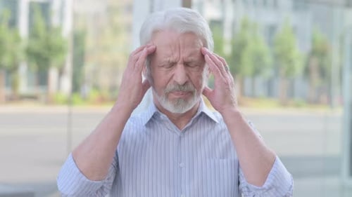 Senior Man Rubbing Temples Experiencing Headache