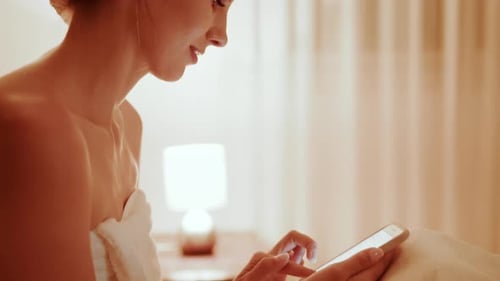 Woman Relaxing in Bed After Spa Using Phone