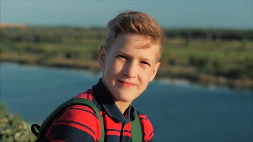 Close Up Portrait Caucasian Boy Teenager in a Red Shirt with a Backpack on His Back, at Sunset