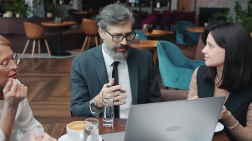 Group of Businesspeople in Formal Clothing Talking Using Computer in Restaurant