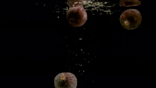Figs falling into water on black background. Bright high quality video