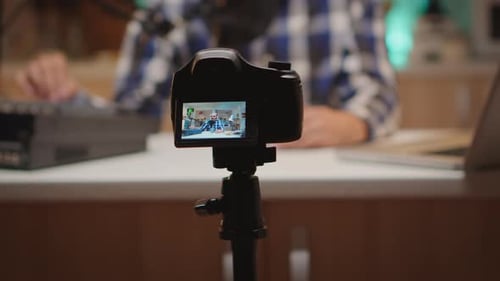 Camera filming man with microphone video blogging at home