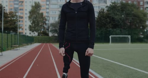 Portrait of Disabled Young Man with Prosthetic Running Blade Standing at Sports Field