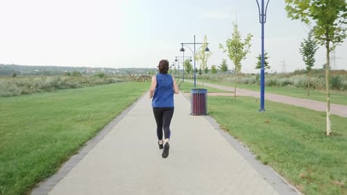 Woman practicing morning jog workout on sports path in morning.