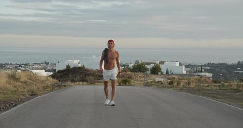 Shirtless Man In Shorts Walking Empty Road